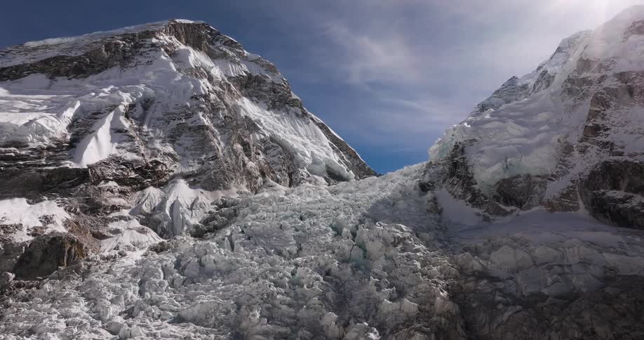 Lots of ice formed between two stone mountains with snow on top