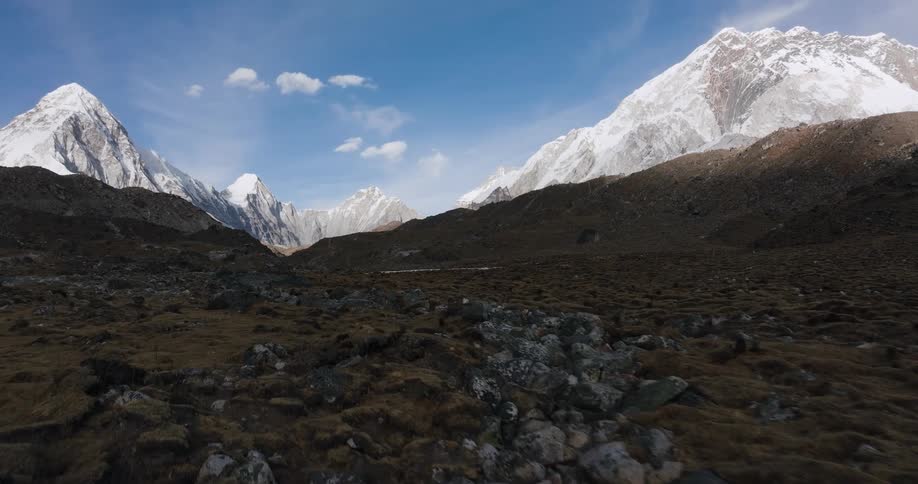 Rocky ground with musicians and surrounding mountain ranges with snow during the day
