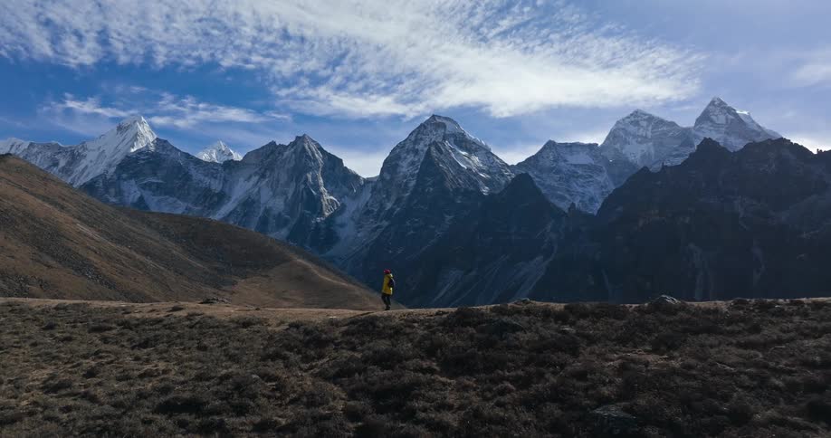 Man walking on a hill overlooking snowcapped mountain ranges