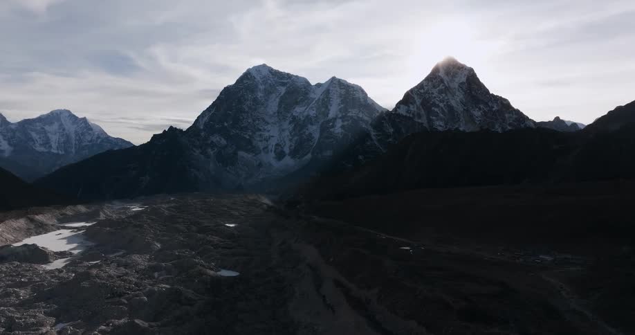 The sun shines over a tall mountain