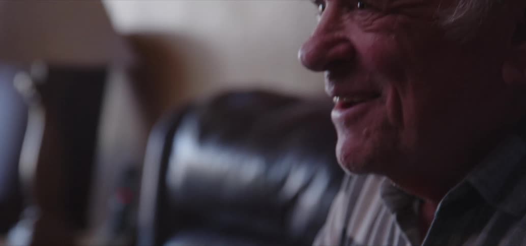 Older man manipulating game controller cheers while sitting on couch