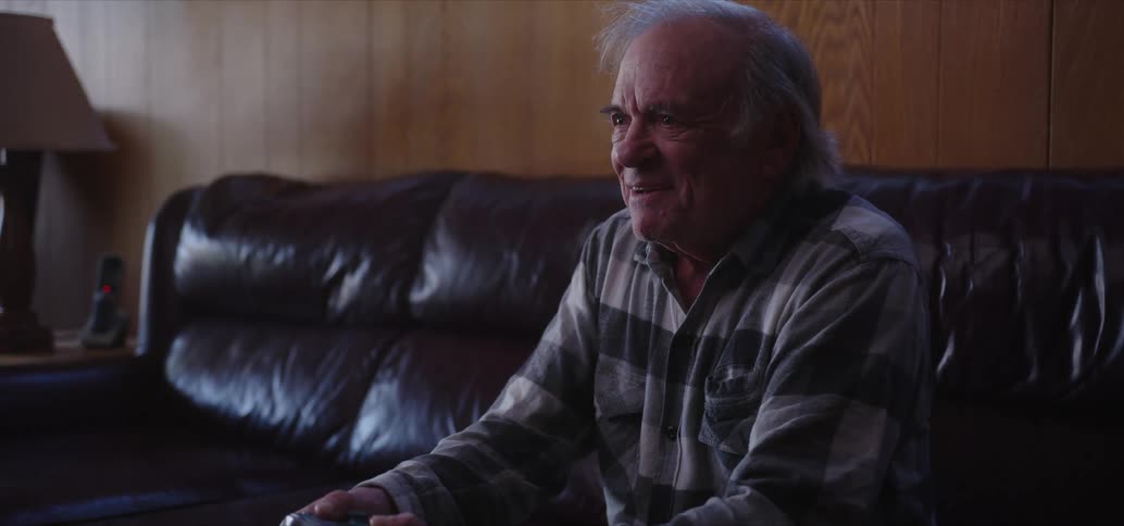 Elderly man sitting in the living room playing video games and cheering