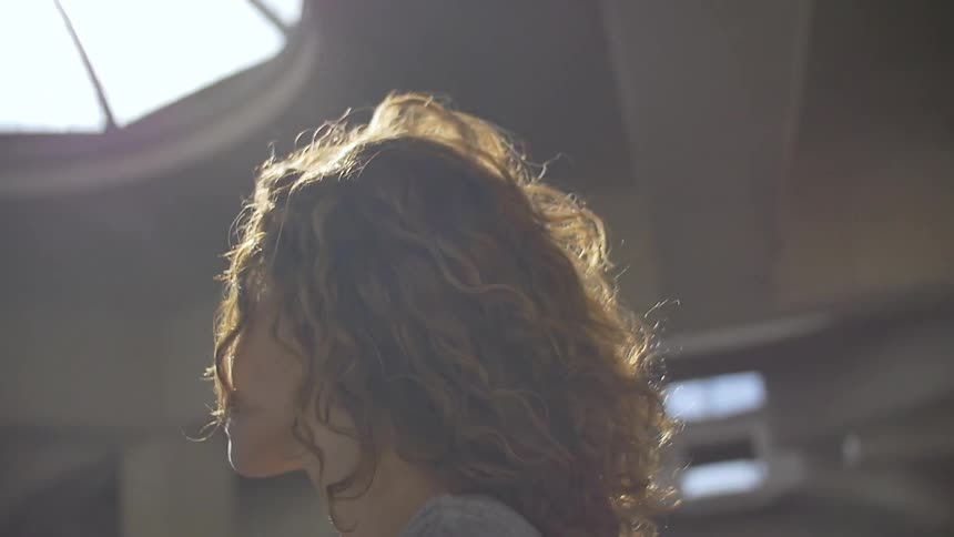A woman inside of a building looking up through the skylight