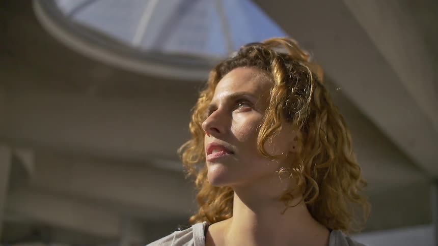 Woman standing inside a building with a skylight looking upwards