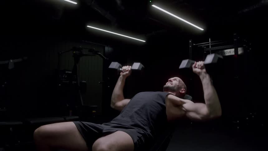 A man working out with some dumbbells in a gym