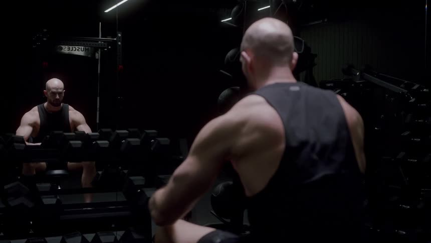 A man is lifting dumbbells in the gym