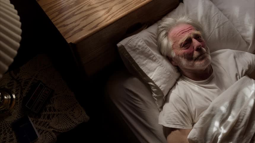 A man wakes up after his alarm rings on a sunny morning