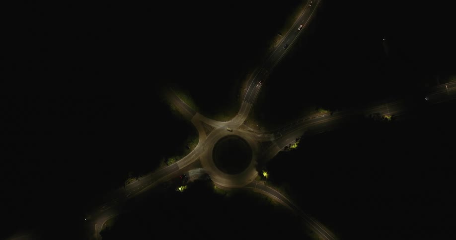 Top view of a roundabout and highways with vehicle traffic at night