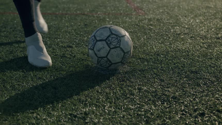 A person sets a soccer ball down on grass