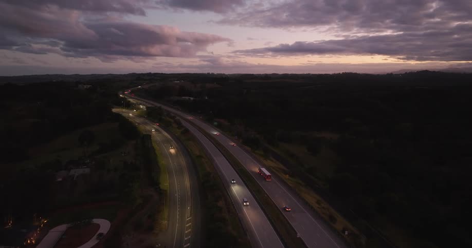 Aerial panorama of a highway in the dark of night with vehicle traffic in a purple sky