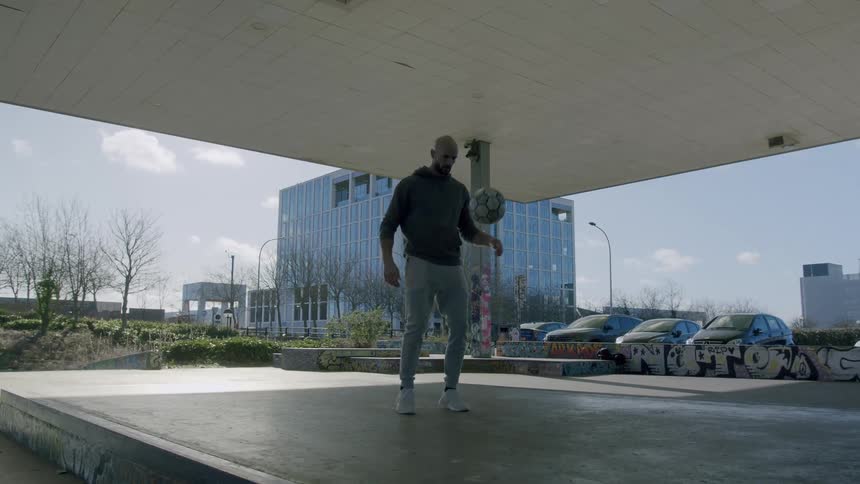 Man juggling soccer ball under a shade during the day