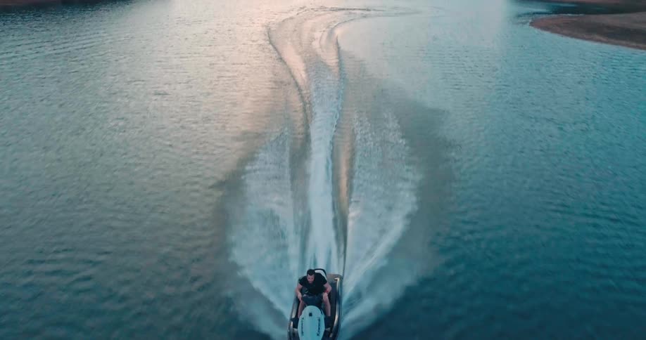 Man riding a jet ski across a lake in the late afternoon