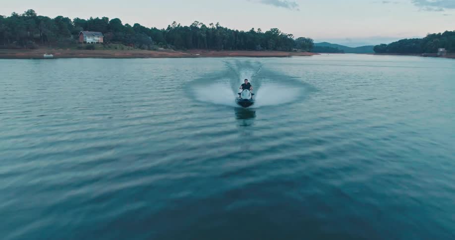 Man riding a jet ski on a lake in the late afternoon