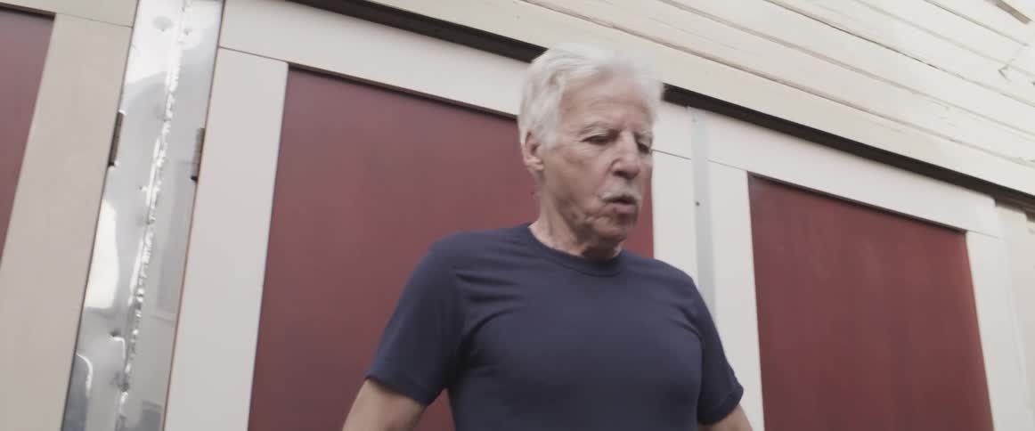 Elderly man testing makeshift shoes in the backyard