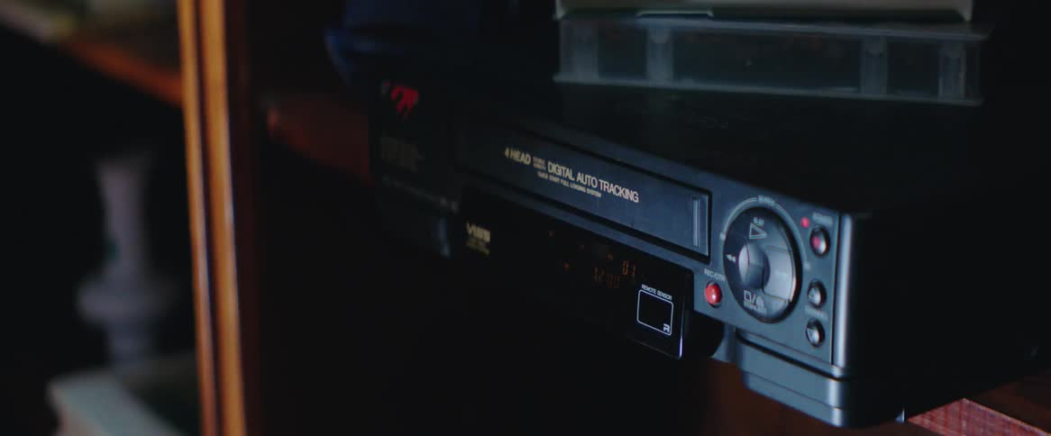 Hands of a person putting a cassette tape into an old dvd
