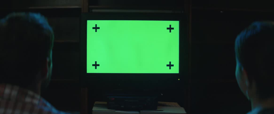 Two people watch a pattern on a television