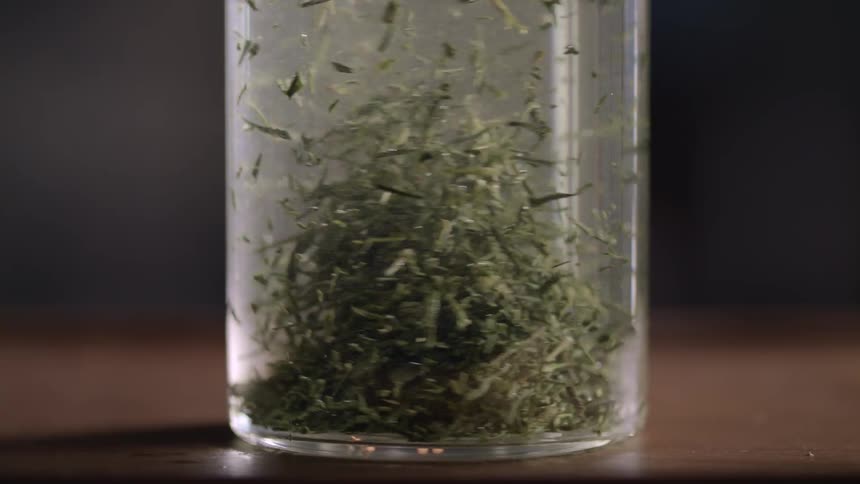 Closeup on a glass with water and herbs rotating in slow motion