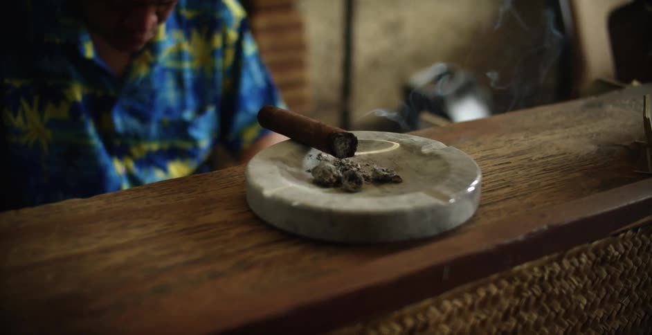 Person looking down while there is a cigar burning
