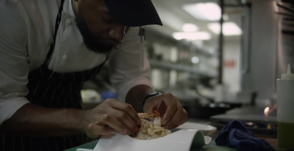 A chef puts food on a plate in the kitchen of a restaurant