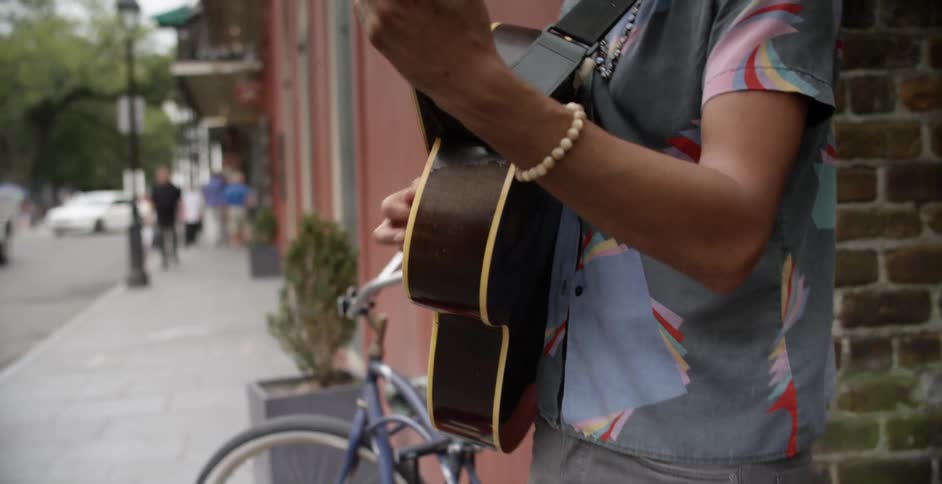 A musician is playing a guitar on a city sidewalk
