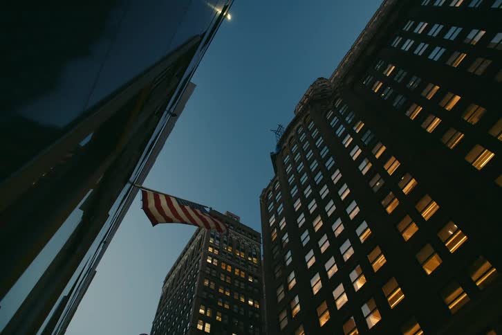 An american flag flies outside of a building in a city