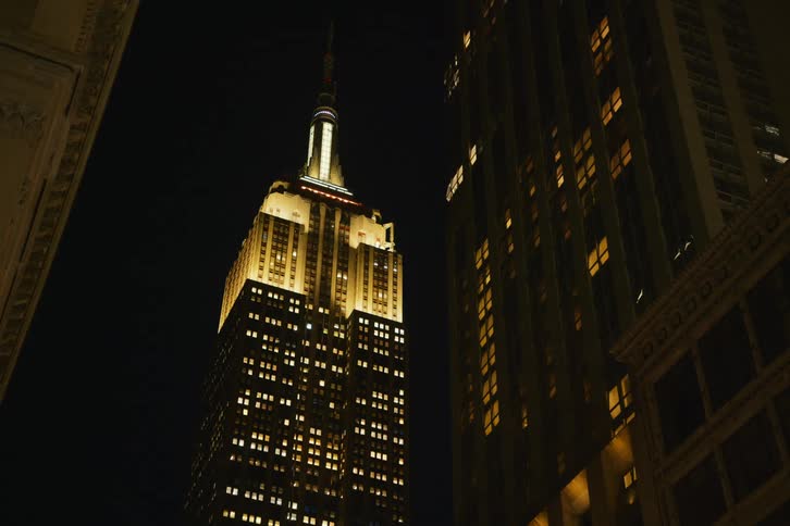 The empire state building is illuminated brightly at night