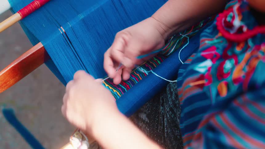 A womans hands weaving a fabric manually