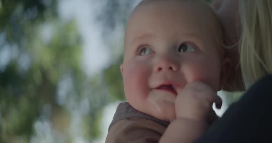 A woman is holding her child in her arm as she shakes him around to calm and make him happy