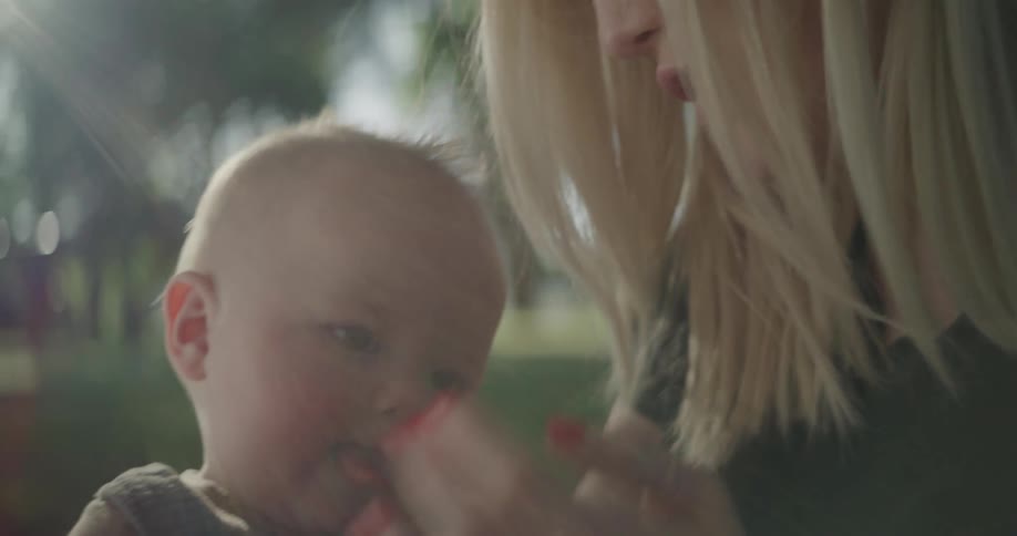 A mother sitting with her baby in a park during the day