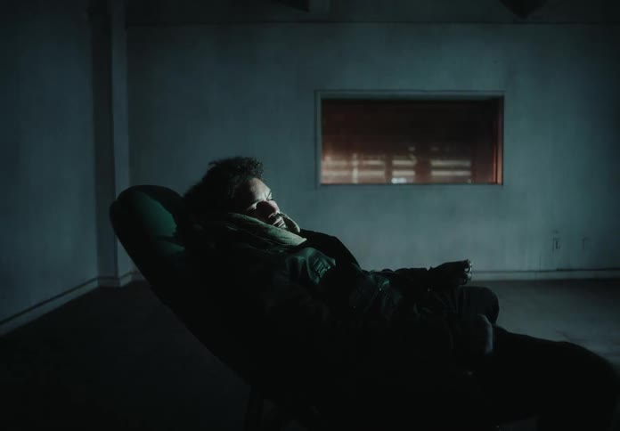 Man sleeping in an armchair inside a room with flashing lights