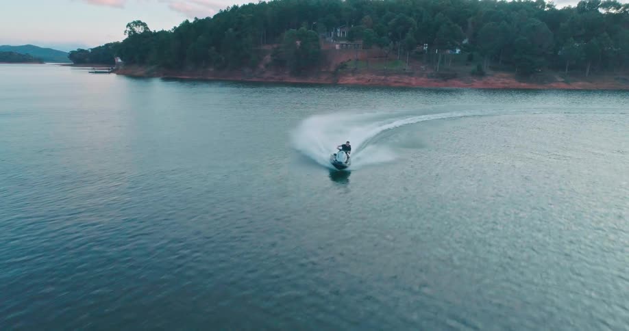 A person riding a jet ski at high speed during sunset