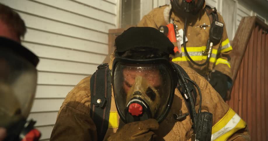 Firefighter leaving the door of a house and meeting his group and everyone celebrating