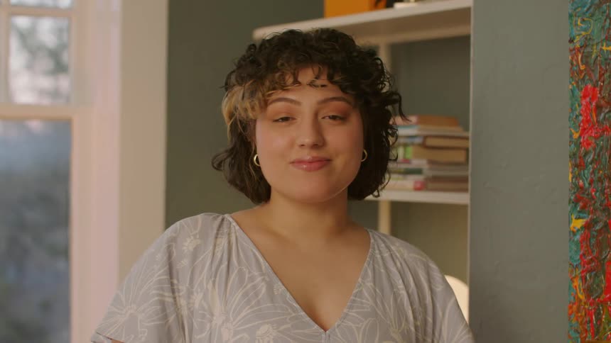 Happy woman smiling standing near a book shelf