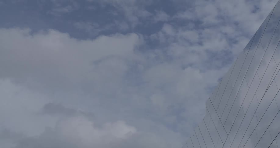 Clouds reflect on the mirror facade of a building