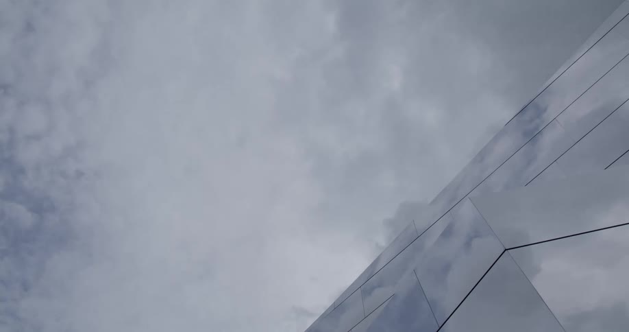 View to the cloudy sky with a portion of a mirrored building