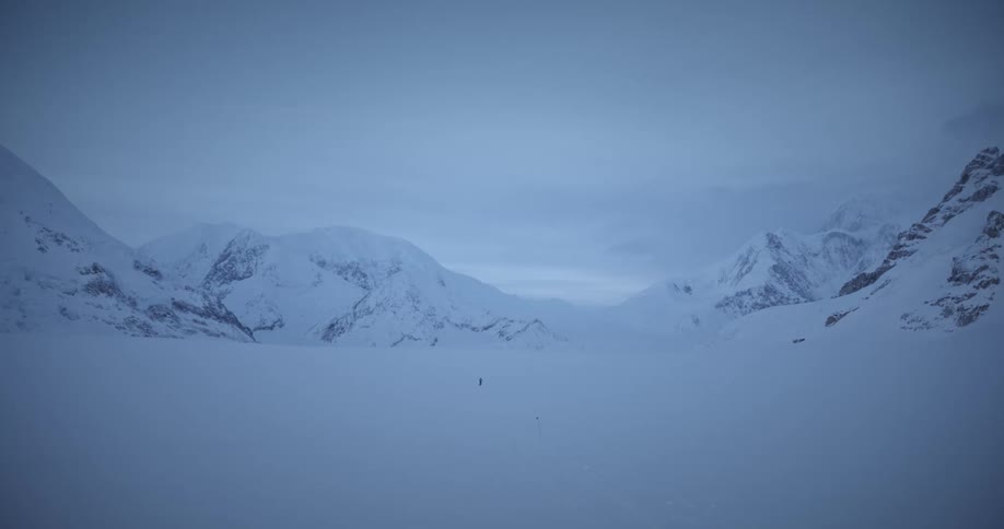 A person walking alone across a snow covered valley