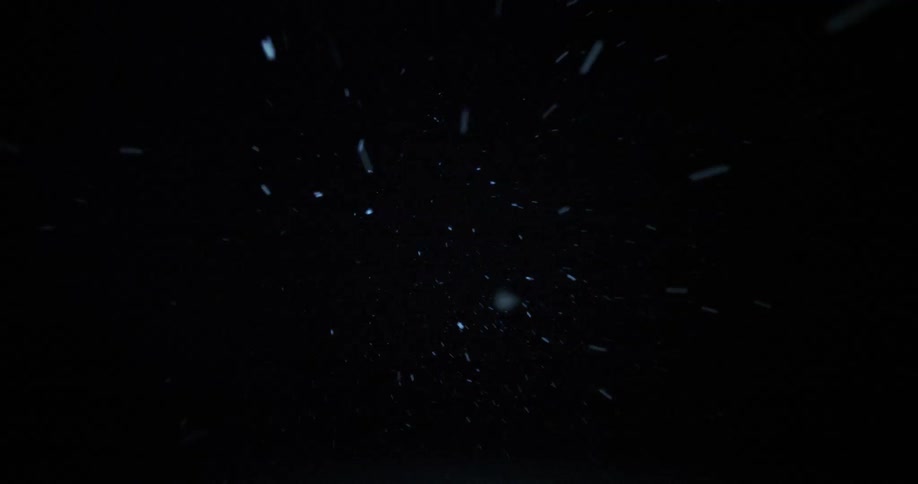 Snow or several small white particles are falling from the sky or a black background