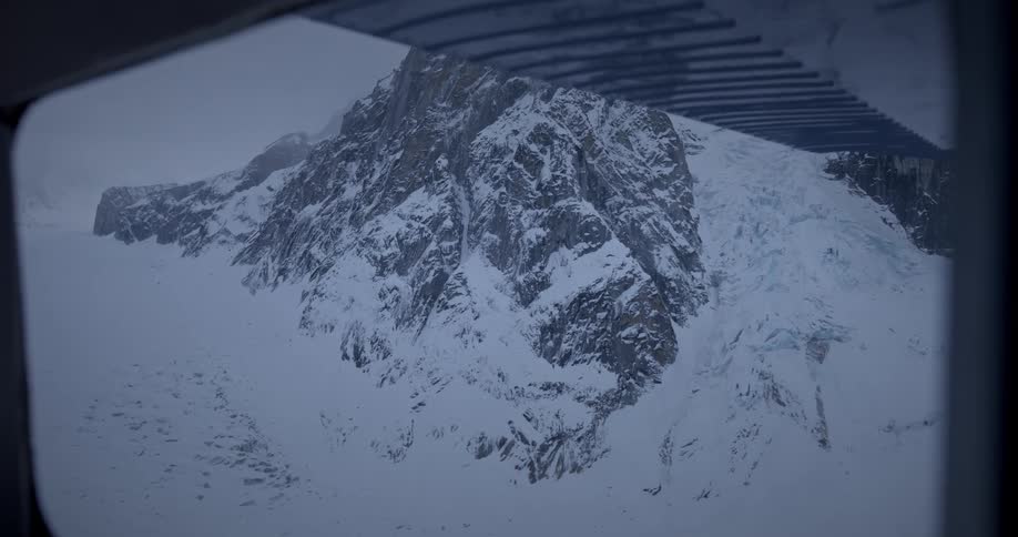 A snowy mountain peak seen from an airplane window