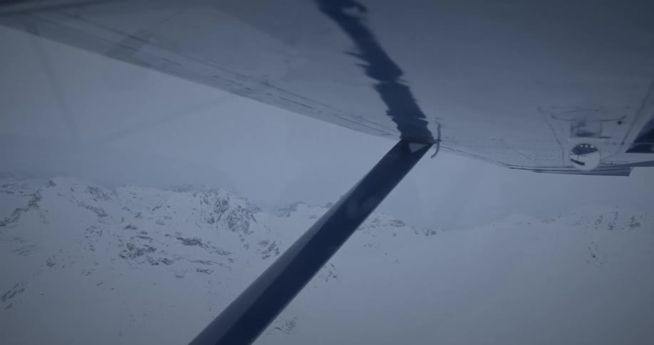Airplane flies over snow covered mountainous terrain