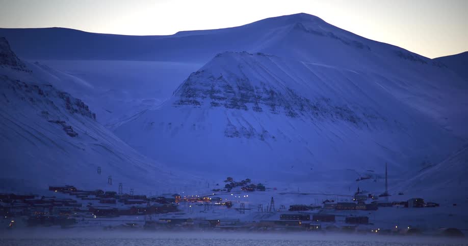 A small coastal town in a landscape with ice mountains