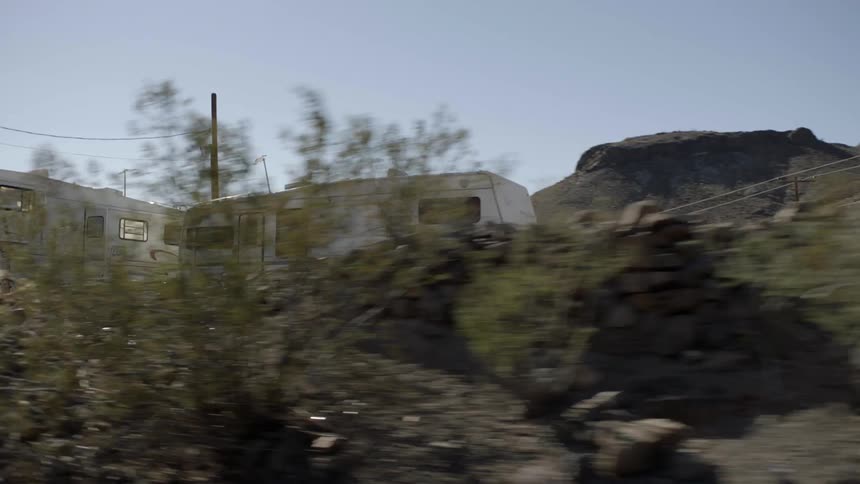 Passing view of two fifth-wheel campers sitting roadside