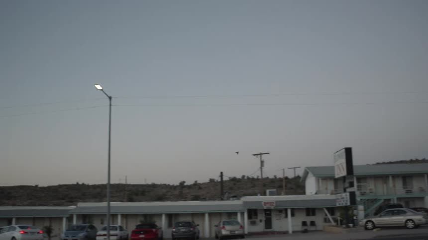 Cars are parked in a lot near some stores at sunset