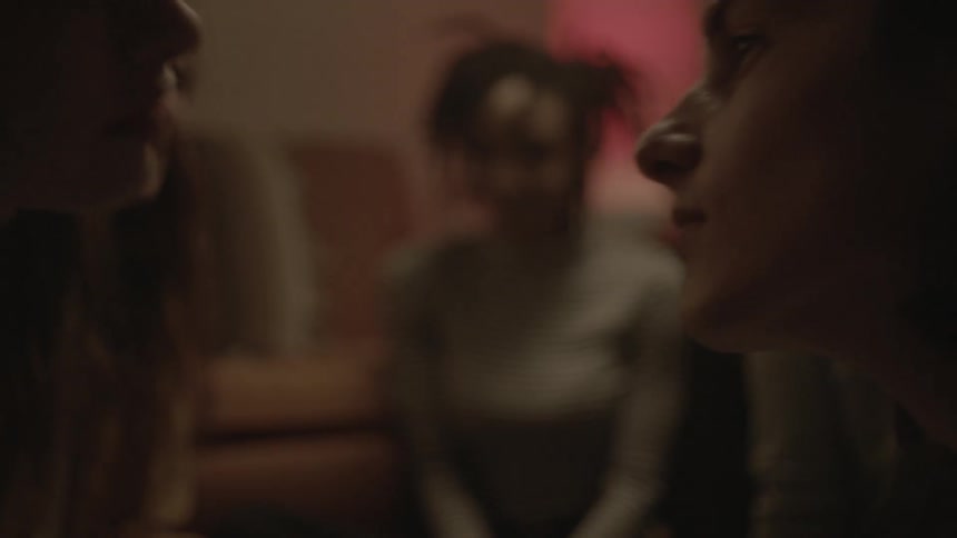 Two people in a home kissing while other people watch