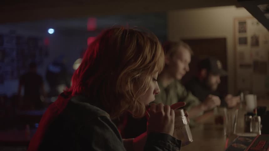 A woman is having a drink in a bar at night