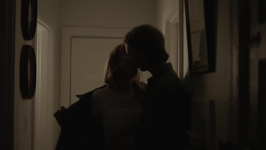 Two teenagers passionately kiss and then move through a door