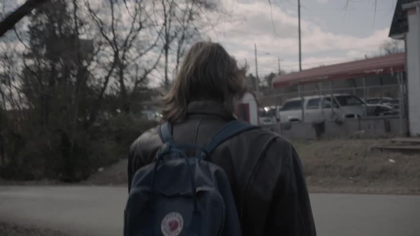 Person wearing a backpack walking down a country road