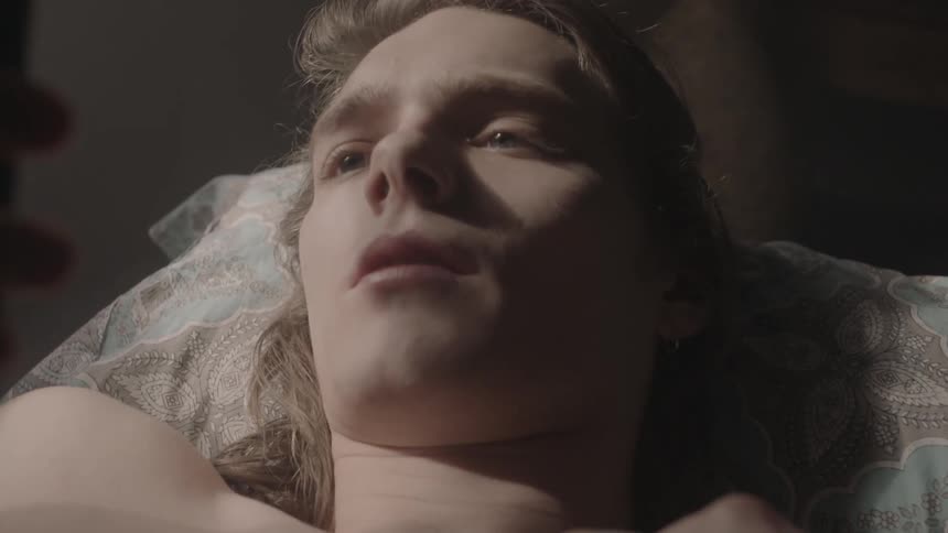 A man laying on a bed staring at his phone