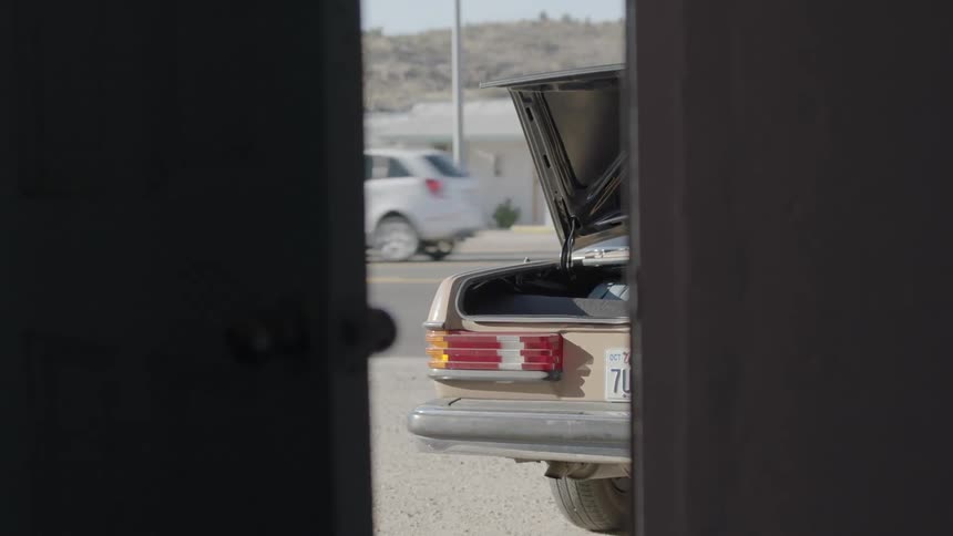 A car trunk is open being filmed through the crack in the door