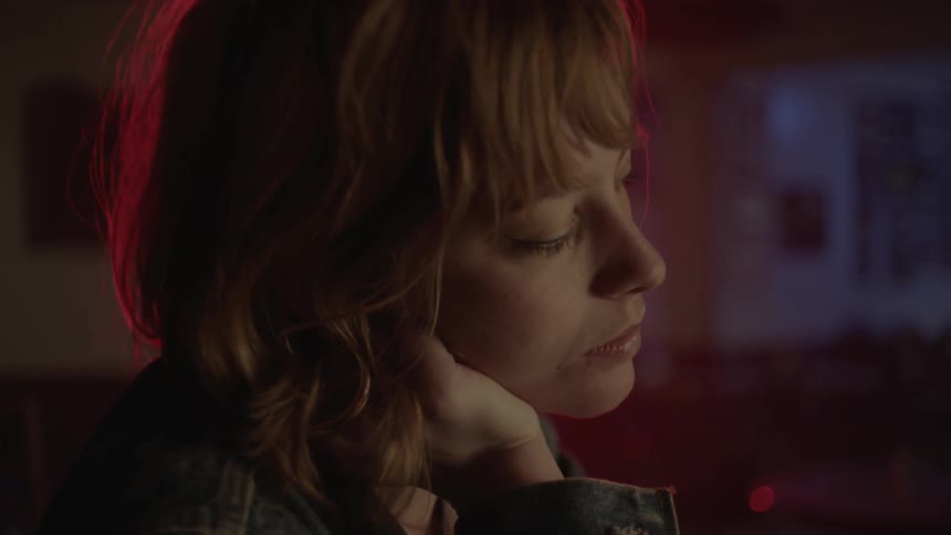 A woman sitting at a bar flirts and smiles