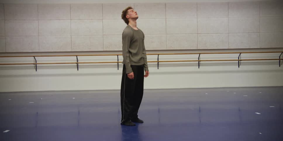 A young boy is finishing dance moves and puts his hands on his face